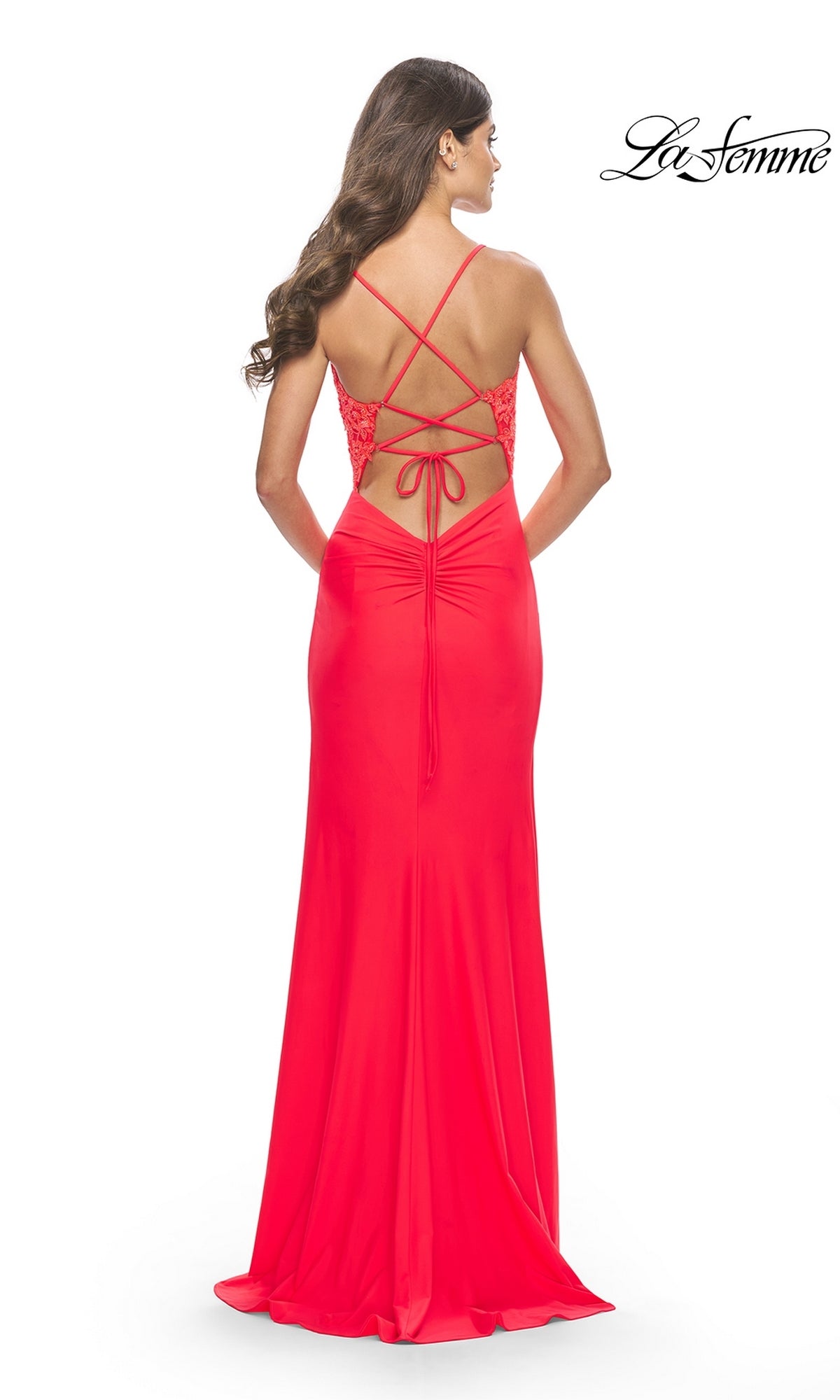 A woman faces away from the camera wearing the Sheer-Bodice Long Prom Dress: La Femme 31447 in bright red, featuring lace detail and crisscross straps on an open back.